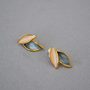 Detail of leaf-shaped earrings with orange and blue-grey enamel in gold plating