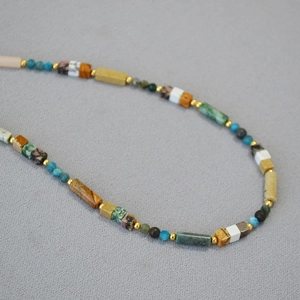 Macro detail of bohemian necklace with colorful natural stone beads and gold accents