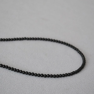 Dettaglio dell'elegante collana di perline in onice nera da 2mm con finitura lucida