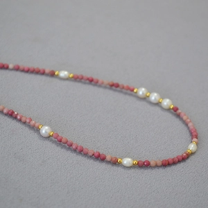 Macro shot of natural pink gemstone beads and freshwater pearls on a dainty necklace