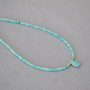 Macro shot of turquoise beaded necklace with a teardrop stone pendant and gold accent beads