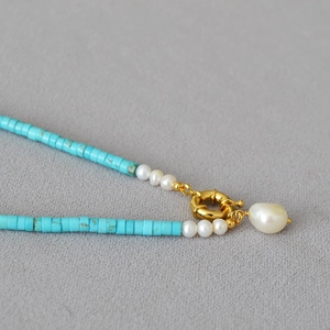 Detail of turquoise beads with baroque pearl pendant and golden spring clasp closure