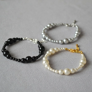Close-up of beaded bracelets with gradient sizes in black, silver, and cream pearls