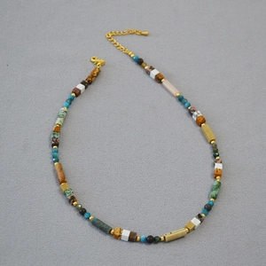 Detail of bohemian necklace featuring colorful natural stones and gold metal accents