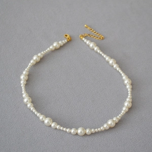 Close-up of gradient white pearl necklace with gold-plated lobster clasp and extender