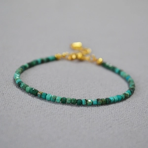 Macro view of minimalist turquoise beaded bracelet with faceted stones and gold clasp
