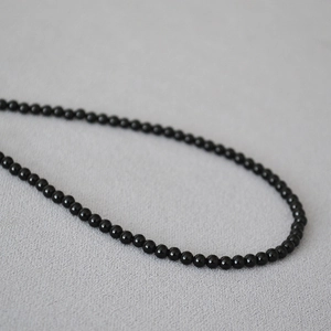 Dettaglio macro di perle di onice nera lucida su un'elegante collana di perle minimalista