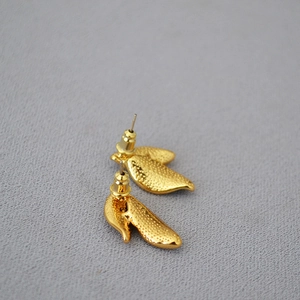 Golden brass leaf-shaped stud earrings with textured embossed finish on grey background