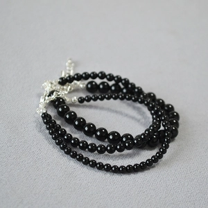 Detailed view of layered black bead bracelets with silver lobster clasps and extension chains