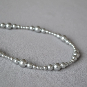 Macro shot of gradient grey and purple pearls on a soft grey fabric background