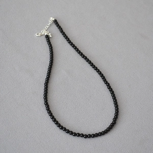 Elegante collana di perle di agata nera con chiusura in argento su tessuto grigio sobrio