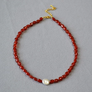 Détail du collier de perles en cornaline rouge et pendentif perle baroque blanche