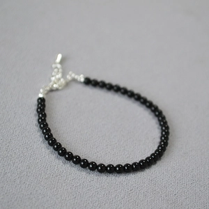 Detail of beaded black onyx bracelet showing silver lobster clasp and extension chain