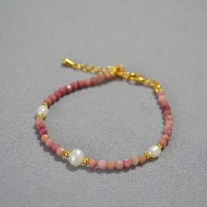 Close-up of pink faceted stones and freshwater pearls on a delicate gold beaded necklace