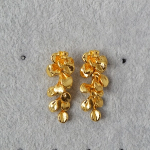 Detail of vintage gold leaf earrings with textured floral design and dangling metal petals
