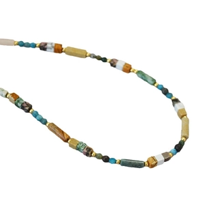 Artistic beaded necklace with natural colorful stones and golden spacers on white background