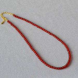 Collier élégant en perles d'agate rouge avec fermoir doré réglable sur fond gris