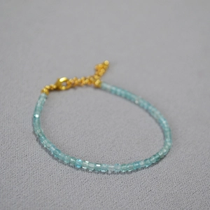 Detailed macro view of faceted aquamarine beads with gold lobster clasp and extension chain