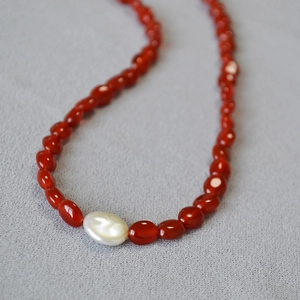 Gros plan détaillé de perles d'agate rouge et d'une perle baroque sur un collier vintage
