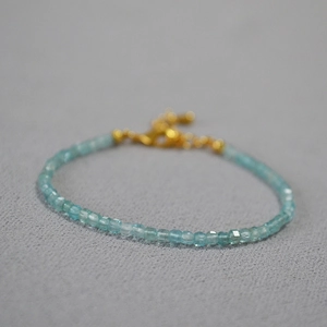 Macro shot of minimalist light blue gemstone beads with gold lobster clasp and extension chain