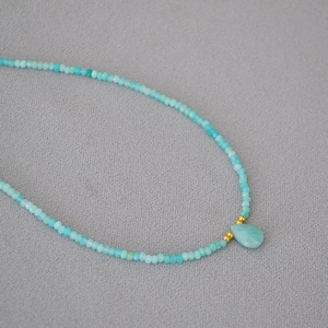 Detail of turquoise beaded necklace with a water drop stone pendant and gold accents