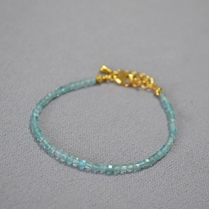 Macro shot of minimalist sky blue cubic beaded bracelet with elegant gold-plated clasp