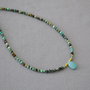 Macro shot of turquoise beaded necklace with a light blue teardrop stone pendant detail