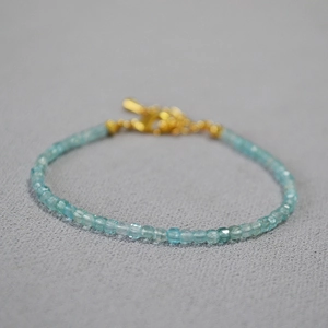 Macro shot of faceted light blue aquamarine square beads with a gold clasp jewelry