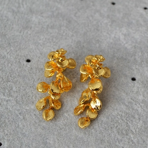 Macro detail of French vintage gold leaf earrings with textured metallic petals and tassels