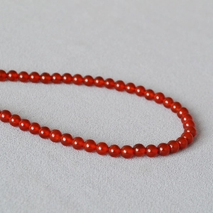 Macro de perles d'agate rouge polies de 4mm montrant texture naturelle et éclat