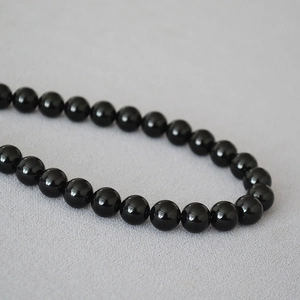Dettaglio di perle di onice nera lucida su una collana con finitura a specchio
