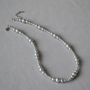 Detail of silver beaded necklace featuring alternating pearl sizes and lobster clasp