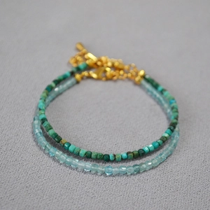 Macro shot of minimalist square blue aquamarine and green stone beaded double bracelets