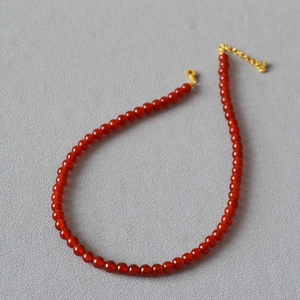 Détail du collier en perles d'agate rouge avec pierres translucides et fermoir doré