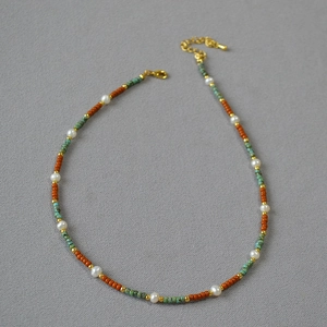 Macro detail of handmade beaded necklace with red beads, turquoise accents and pearls