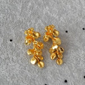 Detailed close-up of French vintage gold leaf earrings with tiered petal design and metal texture