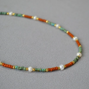 Macro shot of freshwater pearl and orange beaded necklace with vintage gold accents