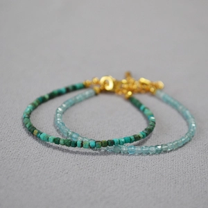 Detailed macro view of square phoenix stone and aquamarine beads with gold chain clasp