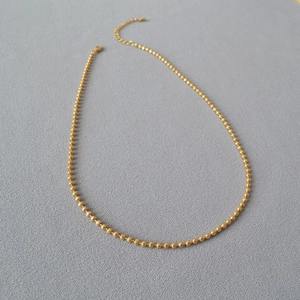 Detail of minimalist gold-plated brass bead chain with lobster clasp and adjustable link