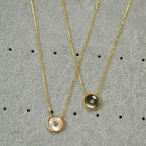 Detailansicht goldener Halsketten mit Anhängern aus schwarzem und weißem Perlmutt