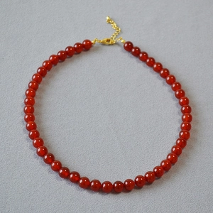 Détail du collier en perles d'agate rouge translucide avec fermoir mousqueton doré