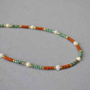 Detailed shot of beaded necklace with freshwater pearls, orange beads and turquoise accents