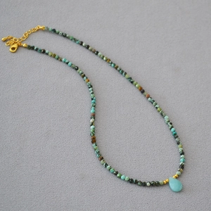 Detailed view of handmade beaded necklace with turquoise stones and blue teardrop pendant