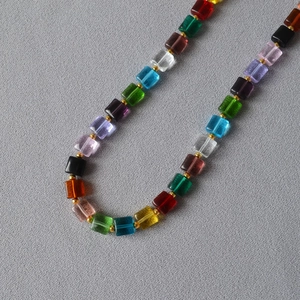 Rainbow colorful transparent square bead necklace with gold spacer accents on grey fabric
