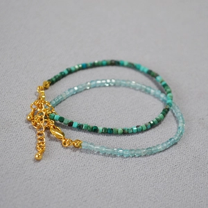 Detail of two-piece beaded bracelets featuring green and light blue faceted cube stones