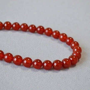 Vue macro d'un collier de perles en agate rouge polie avec finition pierre translucide
