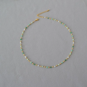 Detailed view of green and white gradient beaded necklace with adjustable gold-tone clasp