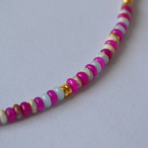 Vue macro d'un collier de perles en résine rose et pierres naturelles colorées