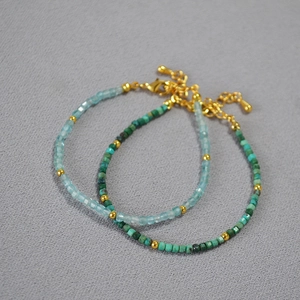 Macro detail of minimalist blue and green stone bead bracelets with 18K gold accents