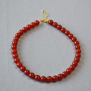Détail d'un collier de perles en agate rouge avec fermoir mousqueton doré et extension